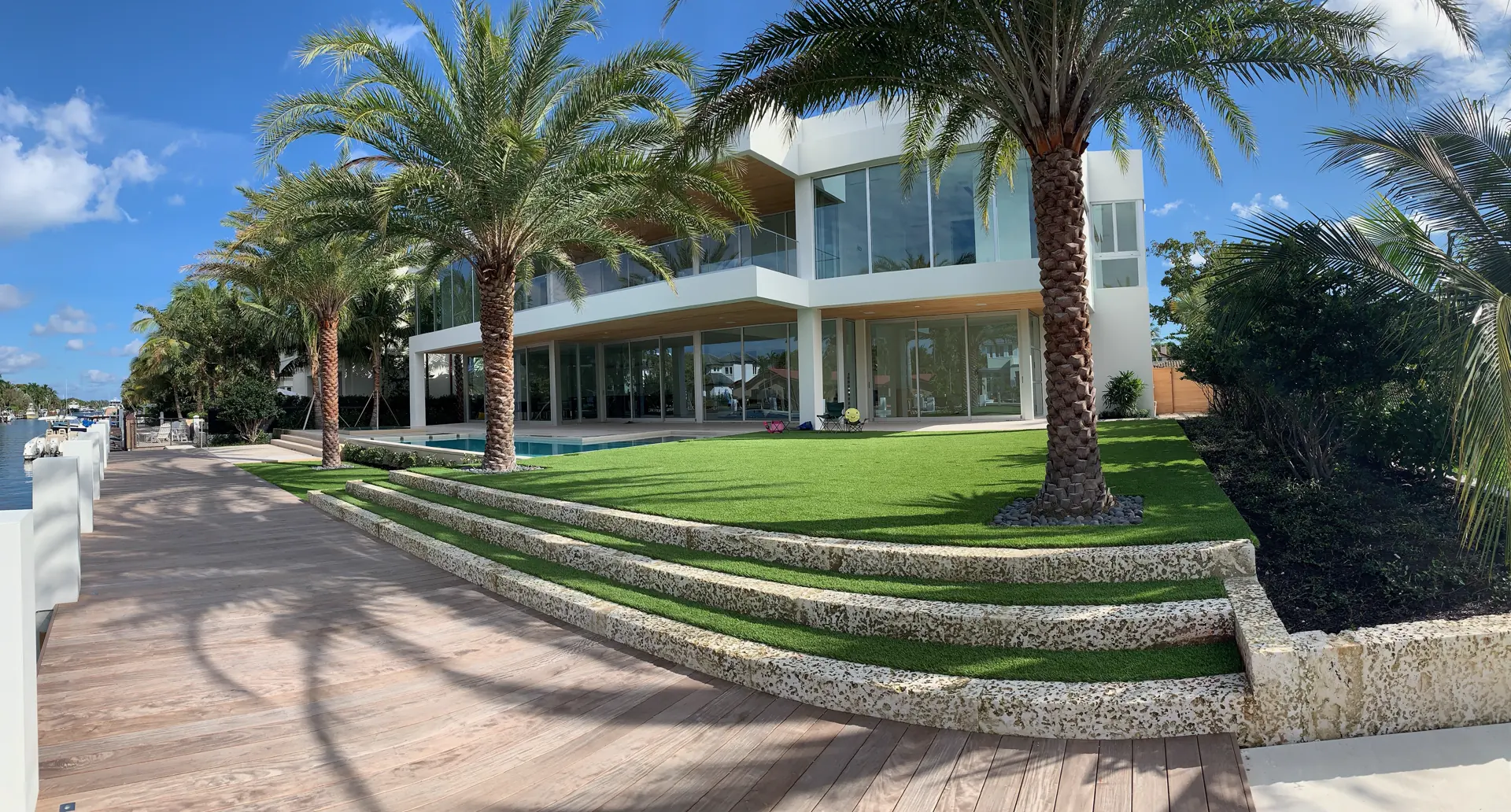 Terraced synthetic turf lawn with palm trees in front of a modern home